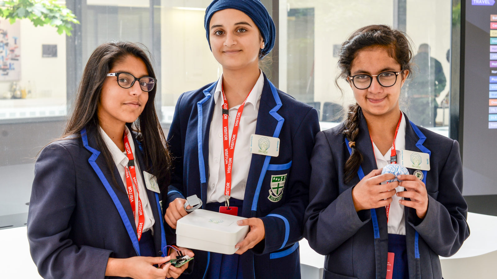 Three female students stand proudly facing the camera