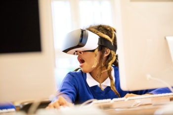 Excited student using virtual reality goggles in the classroom.