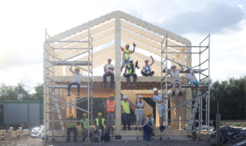 A group of people post in front of a half-finished building structure