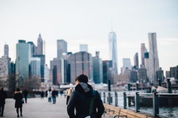 A person is walking away from the camera towards a busy cityscape