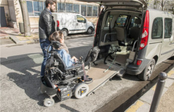 A person in a wheelchair going up a ramp into the back of a vehicle