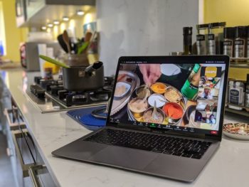 A laptop with dishes of food on the screen in a kitchen environment