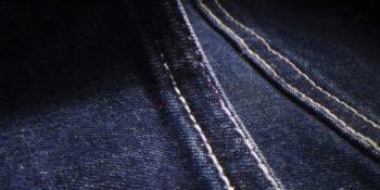 An extreme close up of the stitching detail on dark denim material