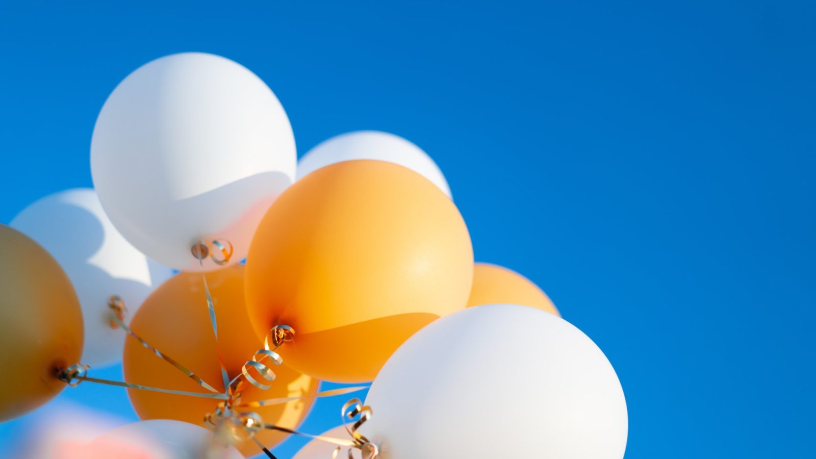 White and yellow balloons against blue sky