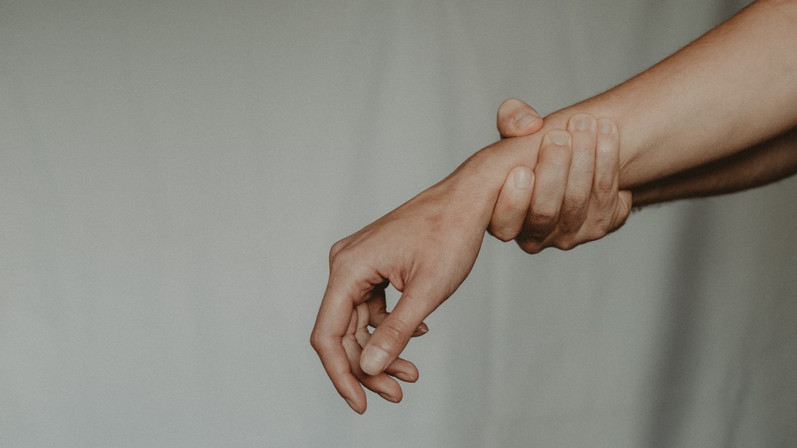 A hand supports the wrist of an outstretched arm