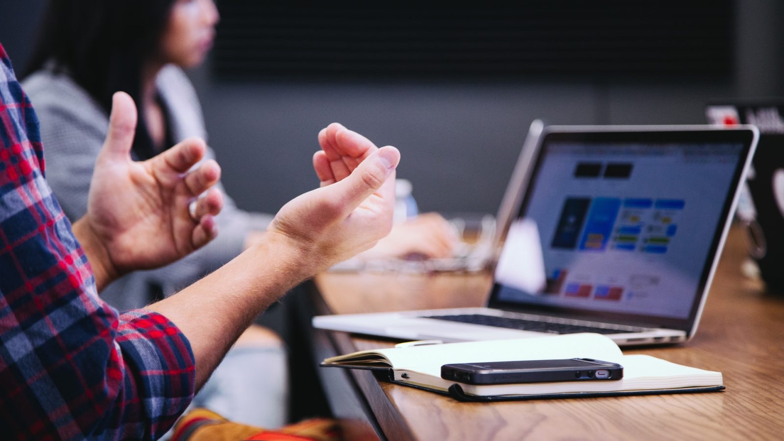 A pair of hands gesturing at a laptop screen