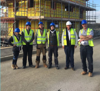 A group of Toolshed trainees stand in a line wearing hardhats and hi vis jackets