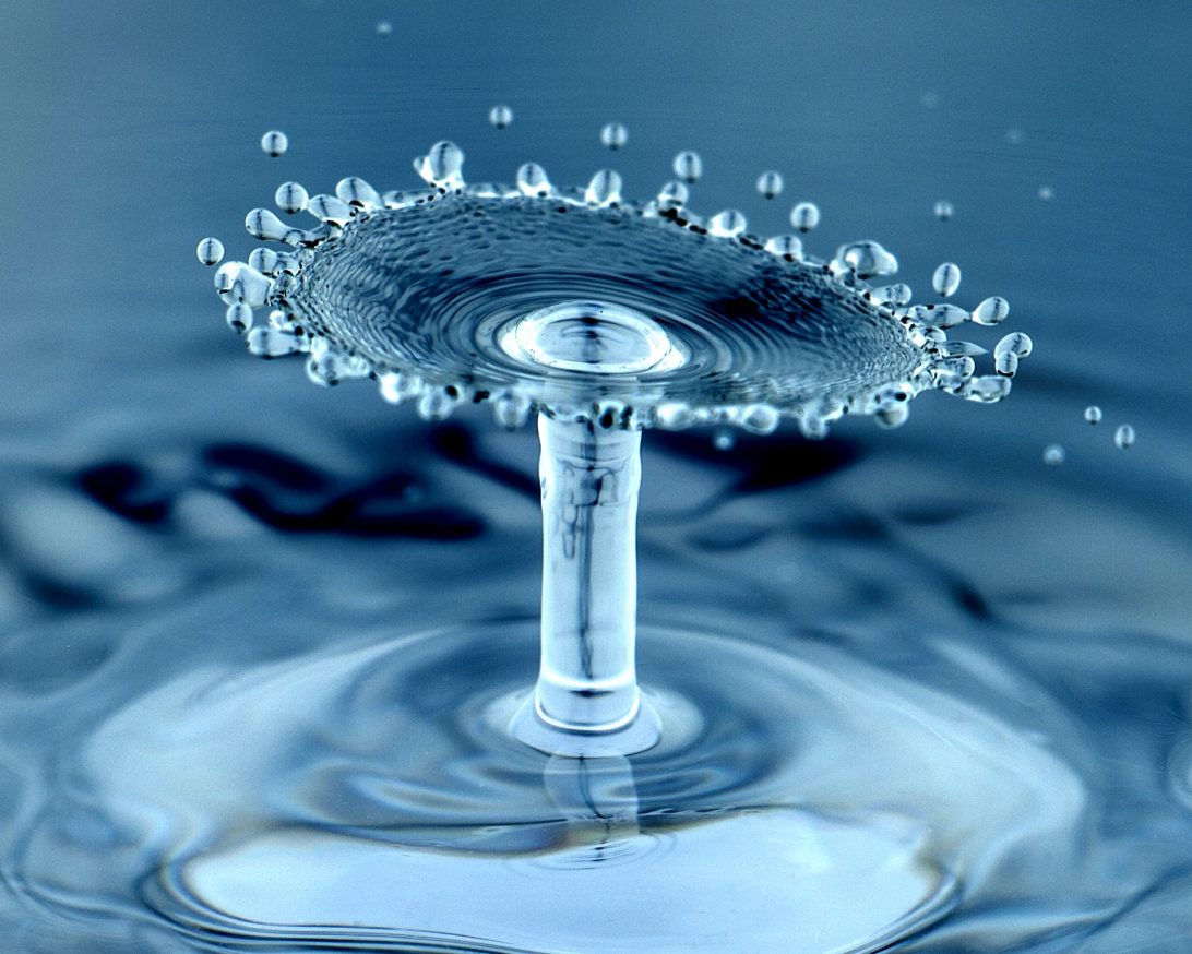 close up of water droplet hitting a larger pool of water