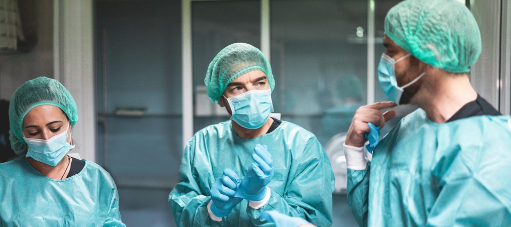 Three doctors wearing full surgical dress and scrubs