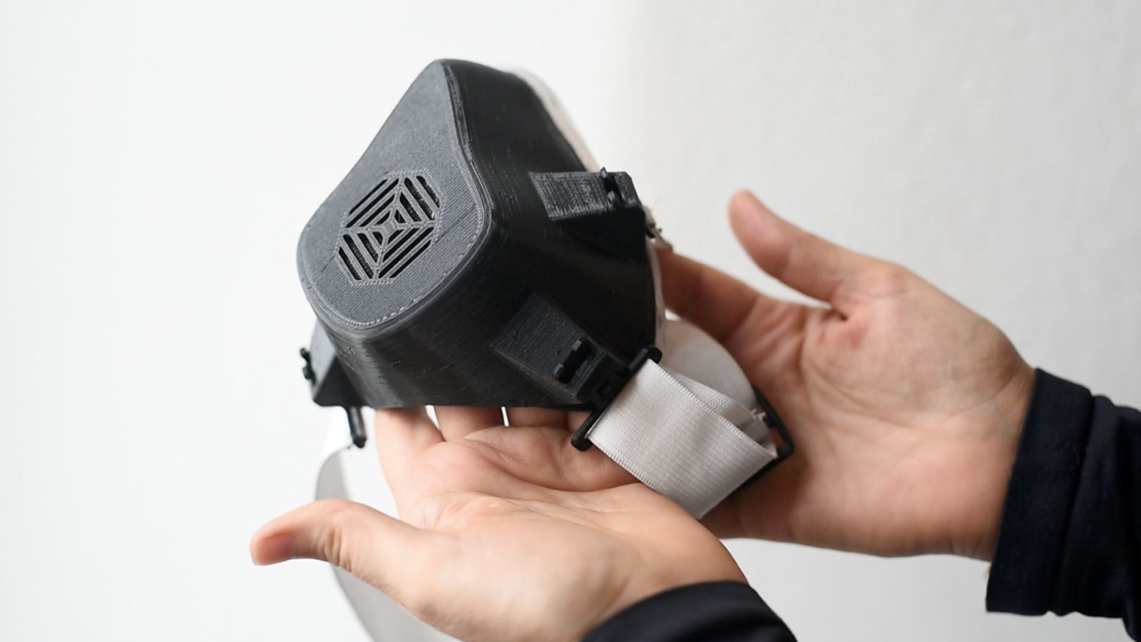 A pair of hands holds up an EPP-1 face mask