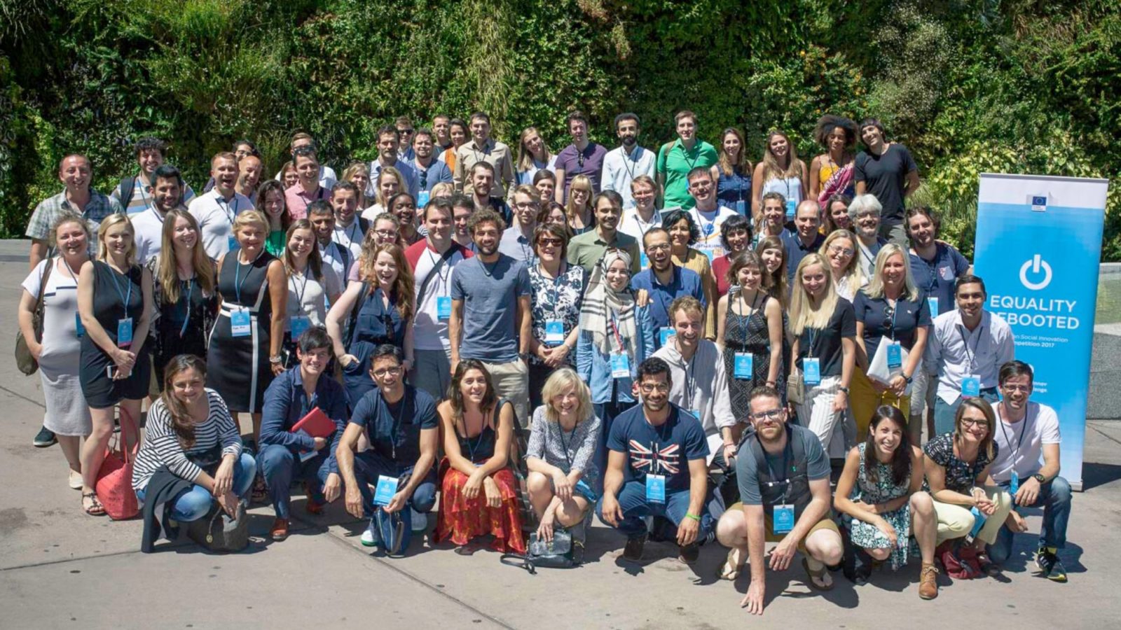 Large crowd of people wearing lanyards from an event outside in the sunshine smiling to camera