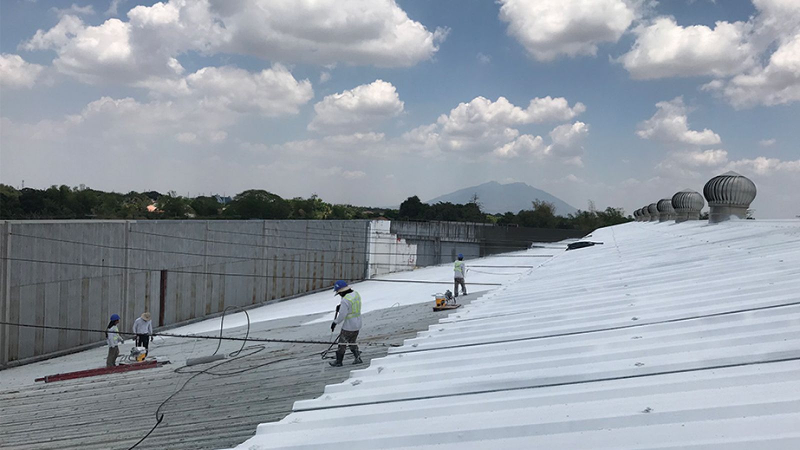 Men work on installing cool roofs in the Philippines