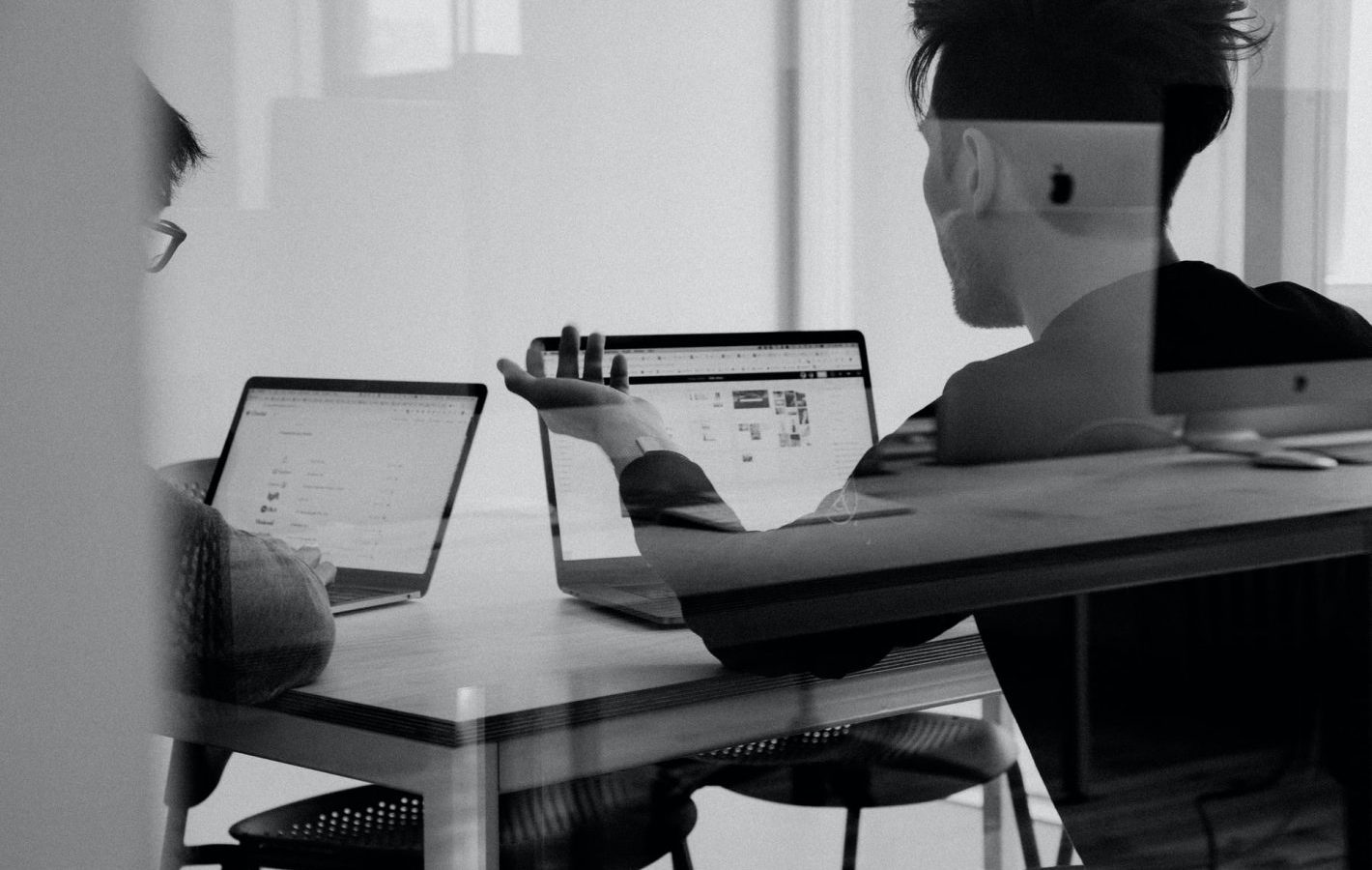 A black and white photo of two people sat at laptops