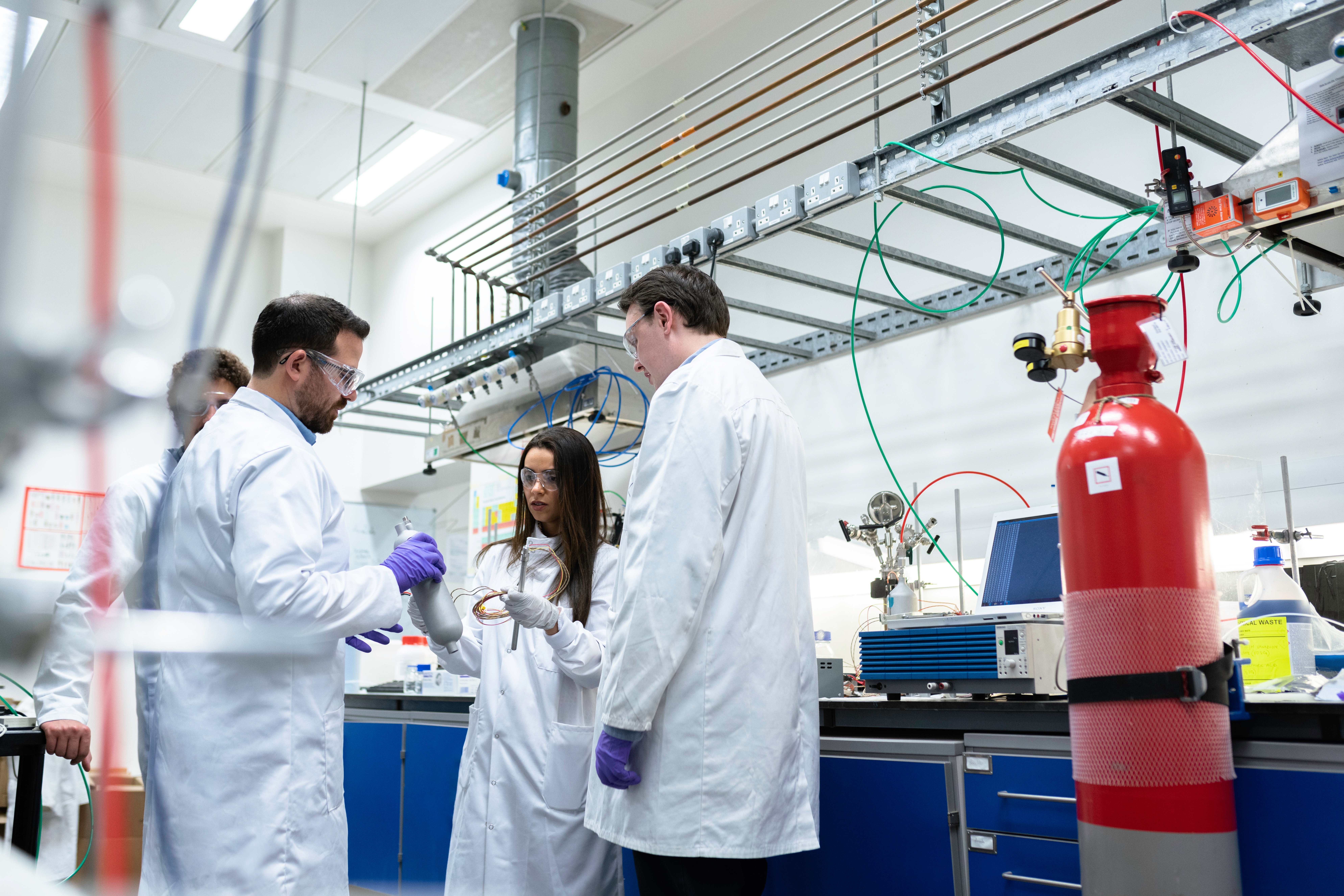 Four engineers standing in white coats in a lab