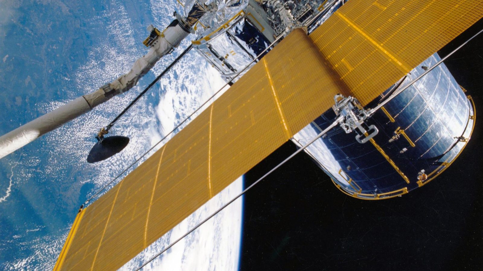 A satellite with a yellow sail flies above the earth through space