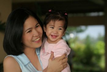 Asian woman holding a child, dressed in pink