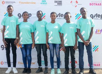 Group of young people in turquoise t-shirts standing in front of a printed banner