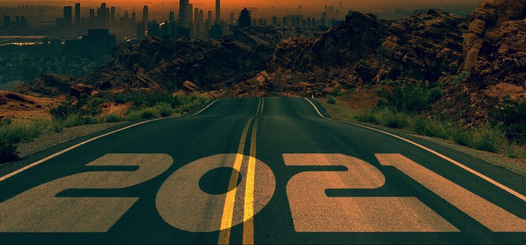 A road with 2021 painted on it disappears into the distance|A toy TARDIS made out of Lego