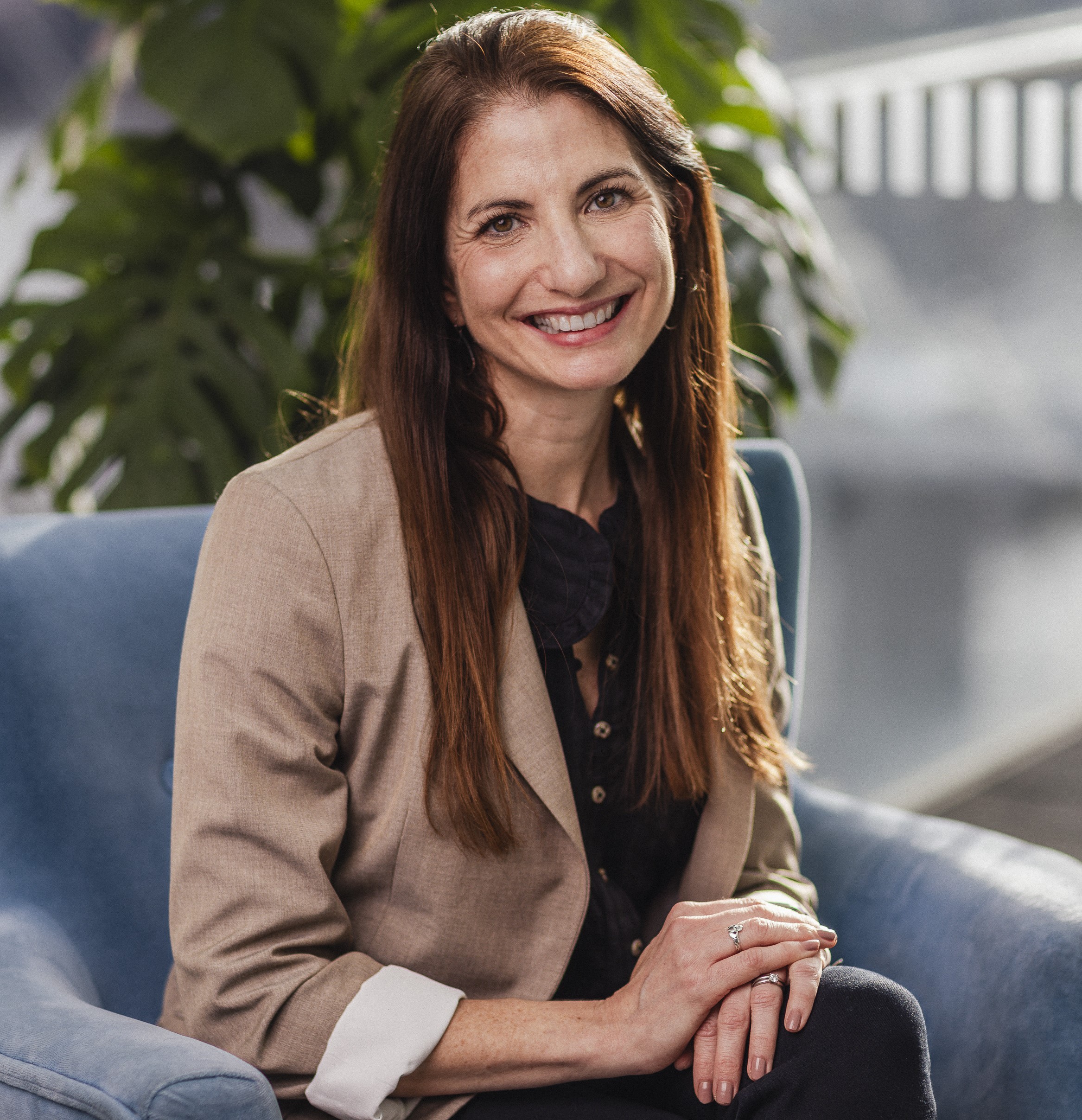 ||Photo of a women in a brown blazer with long brown hair