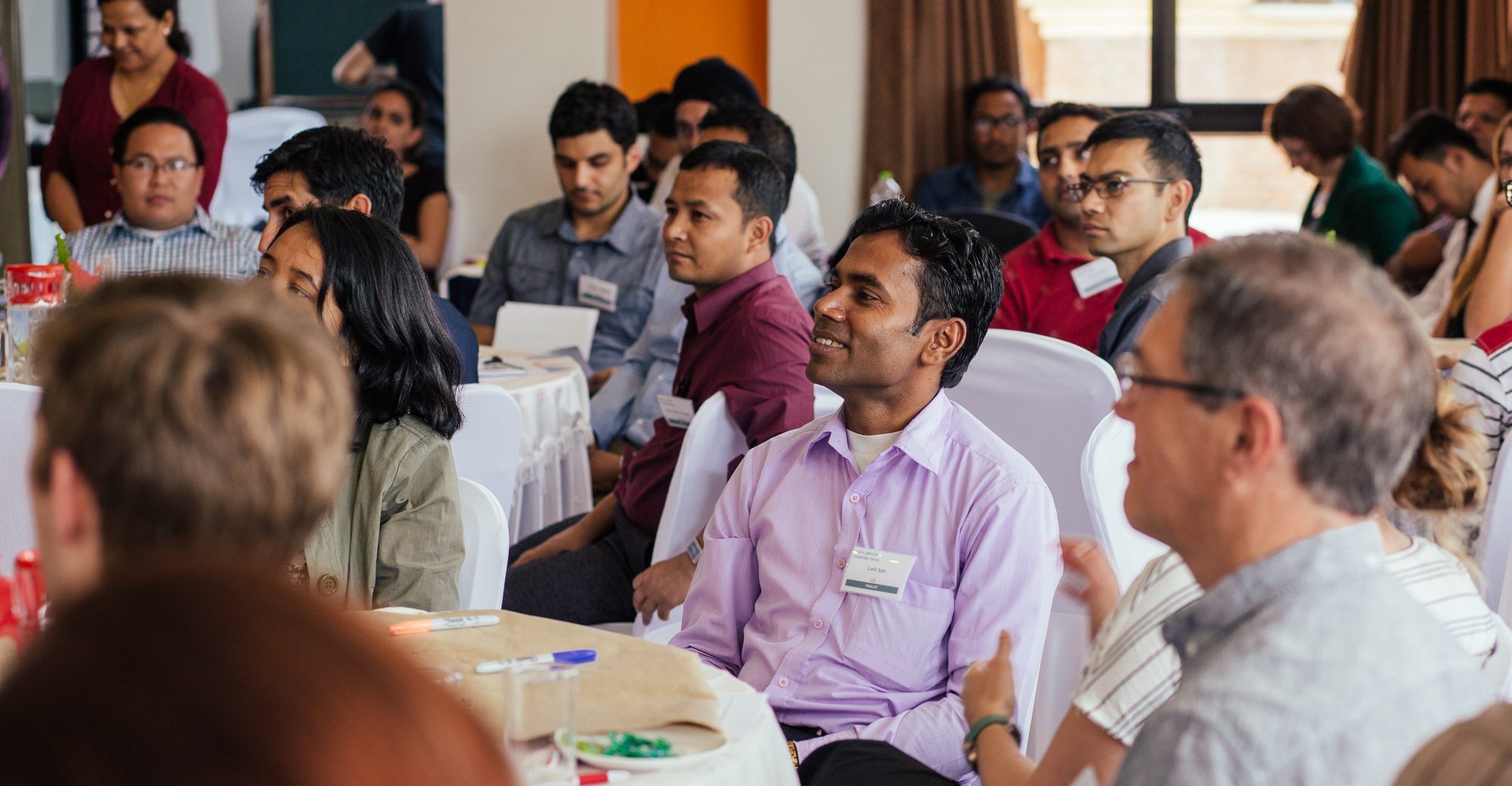 Groups of people gathered around round tables|Map of the world showing where Challenge Works has supported teams