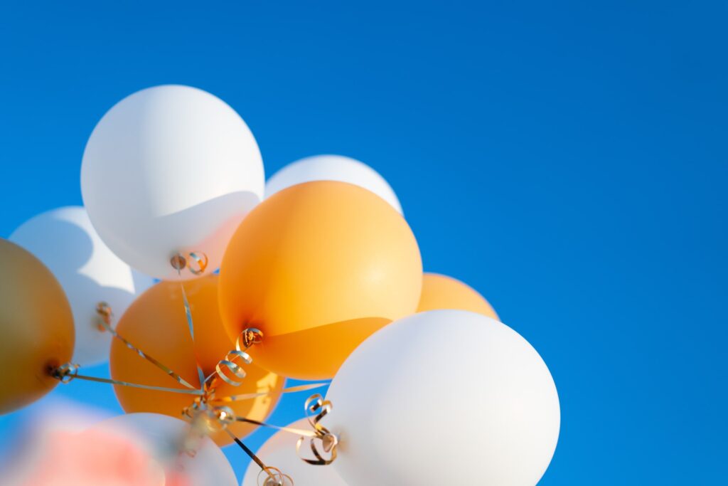 White and yellow balloons against blue sky|green