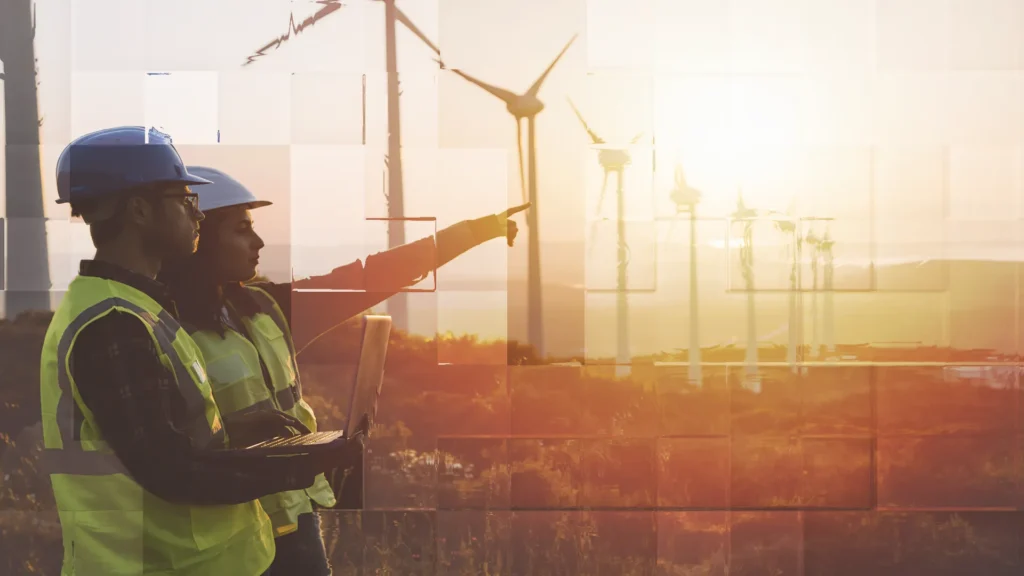 two people pointing with wind turbines lit up behind them