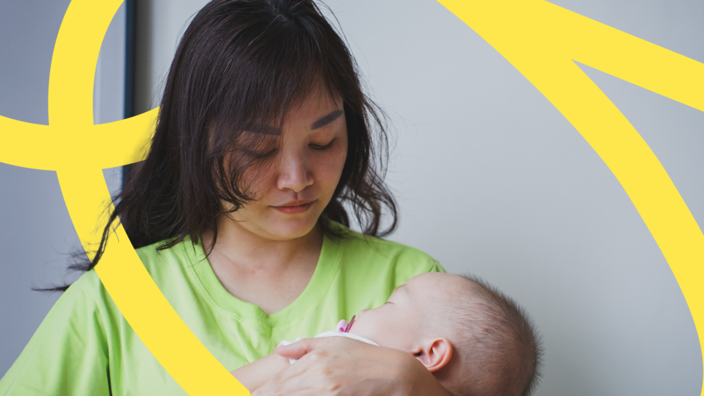 |Women holding a baby with a spoon in her hand.|woman holding a young baby|A women with a child on her back surrounded by trees and plants