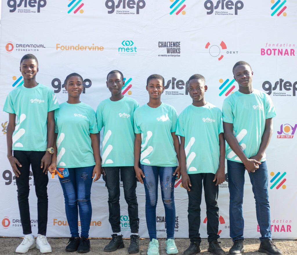 Group of young people in turquoise t-shirts standing in front of a printed banner