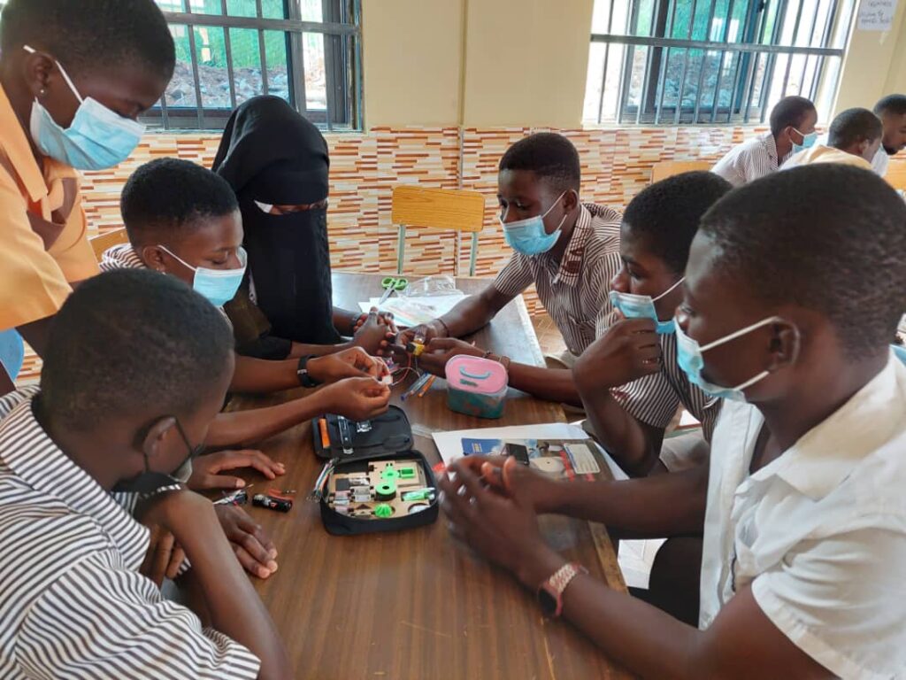 Ghanaian students sit around a table and work on a science project|