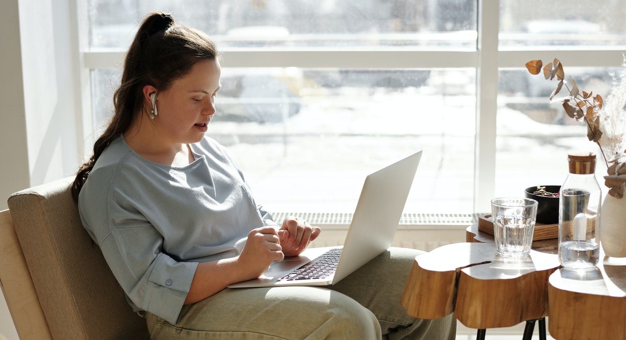 Girl sitting at a table by a window with a laptop|A younger woman on the left and an older man on the right have tea and enjoy a chat.