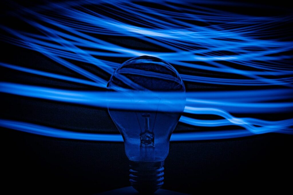 Blue and white light filaments and lightbulb|Grey and white smart home device|Wind turbine against a blue sky|The International Space Station||A contactless payment being made via a mobile phone
