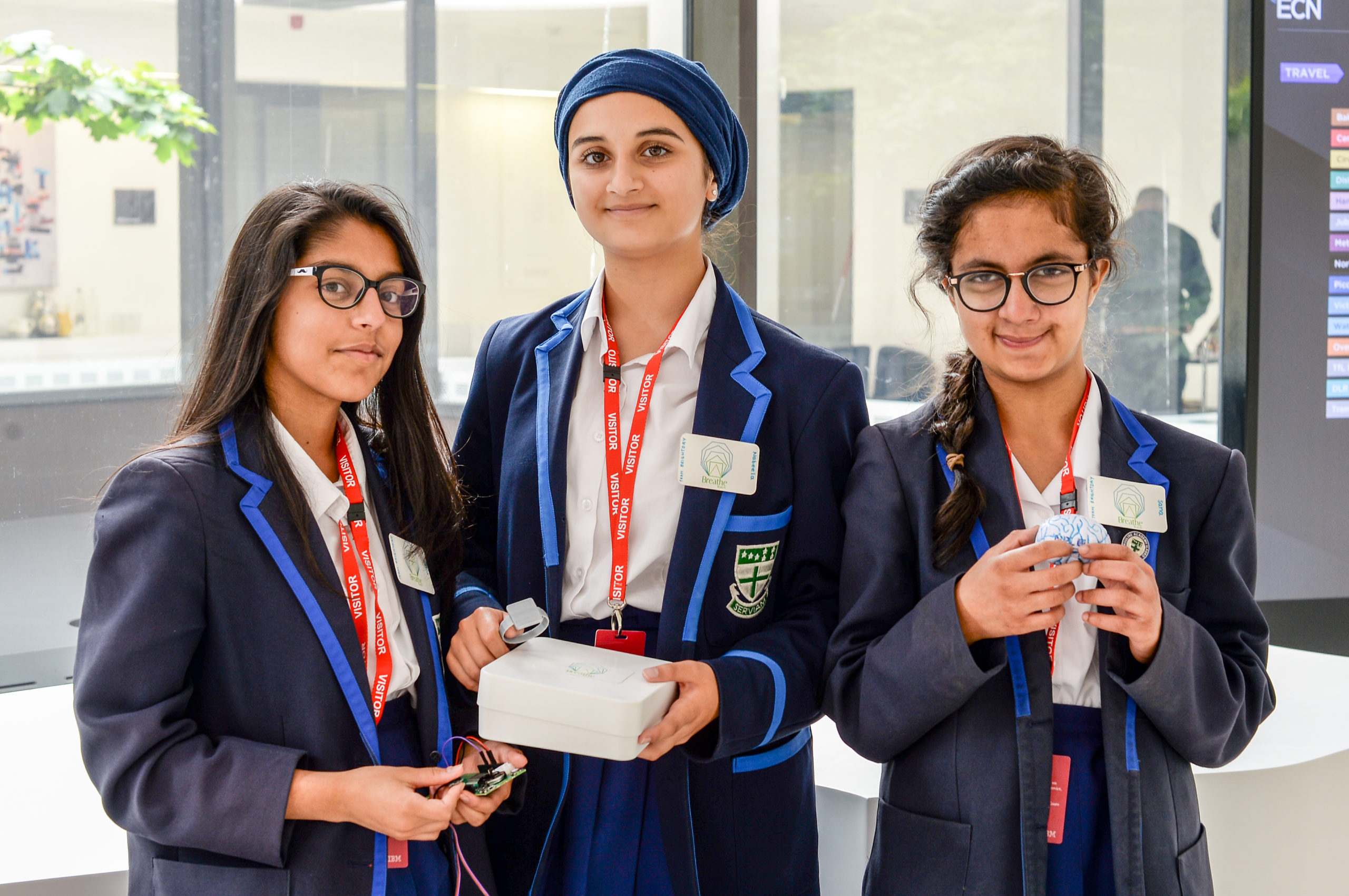 Three female students stand proudly facing the camera