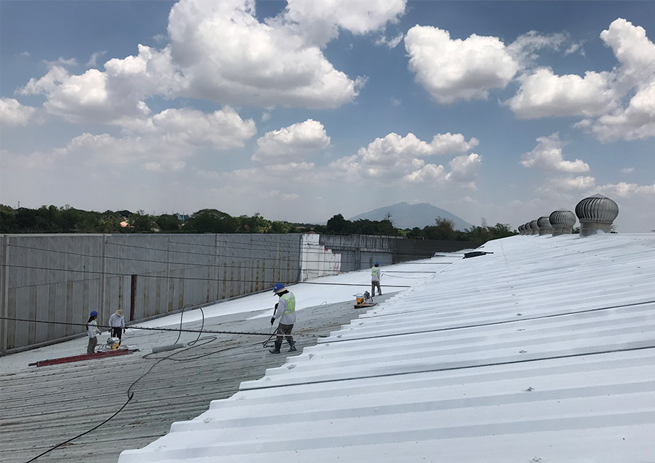 Men work on installing cool roofs in the Philippines