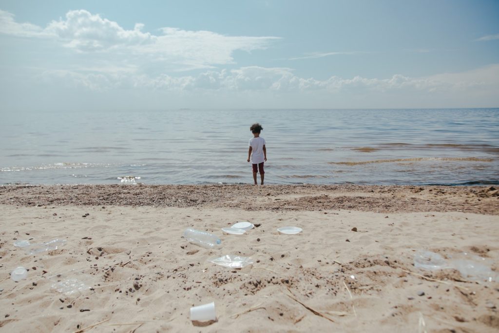 figure of a small child stood by the shore of a beach