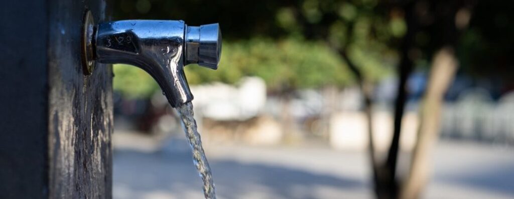 A silver tap mounted on a wall with water flowing from it