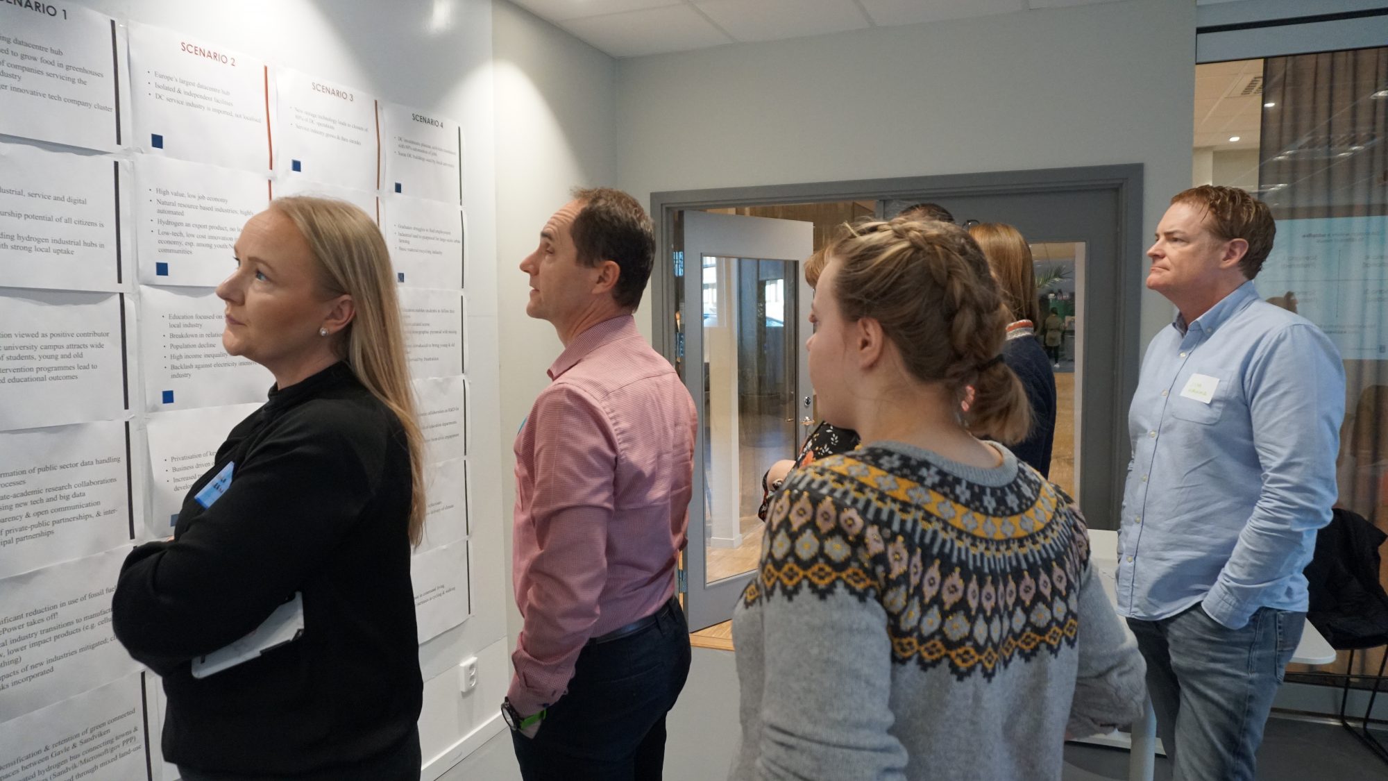 Four people stand in an office looking at a whiteboard covered in notes|Apollo Solar Technology water heater being maintained or installed on roof