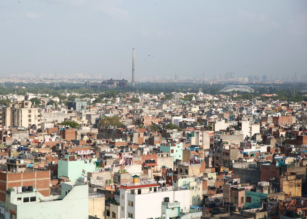 White and brown concrete buildings shot from a distance|An overhead shot of a selection of one-storey buildings|Two rectangular tool boxes|People shopping on a high street in the Midlands|Green lily pads on calm water|A cool roof pilot program in the town of Kheis