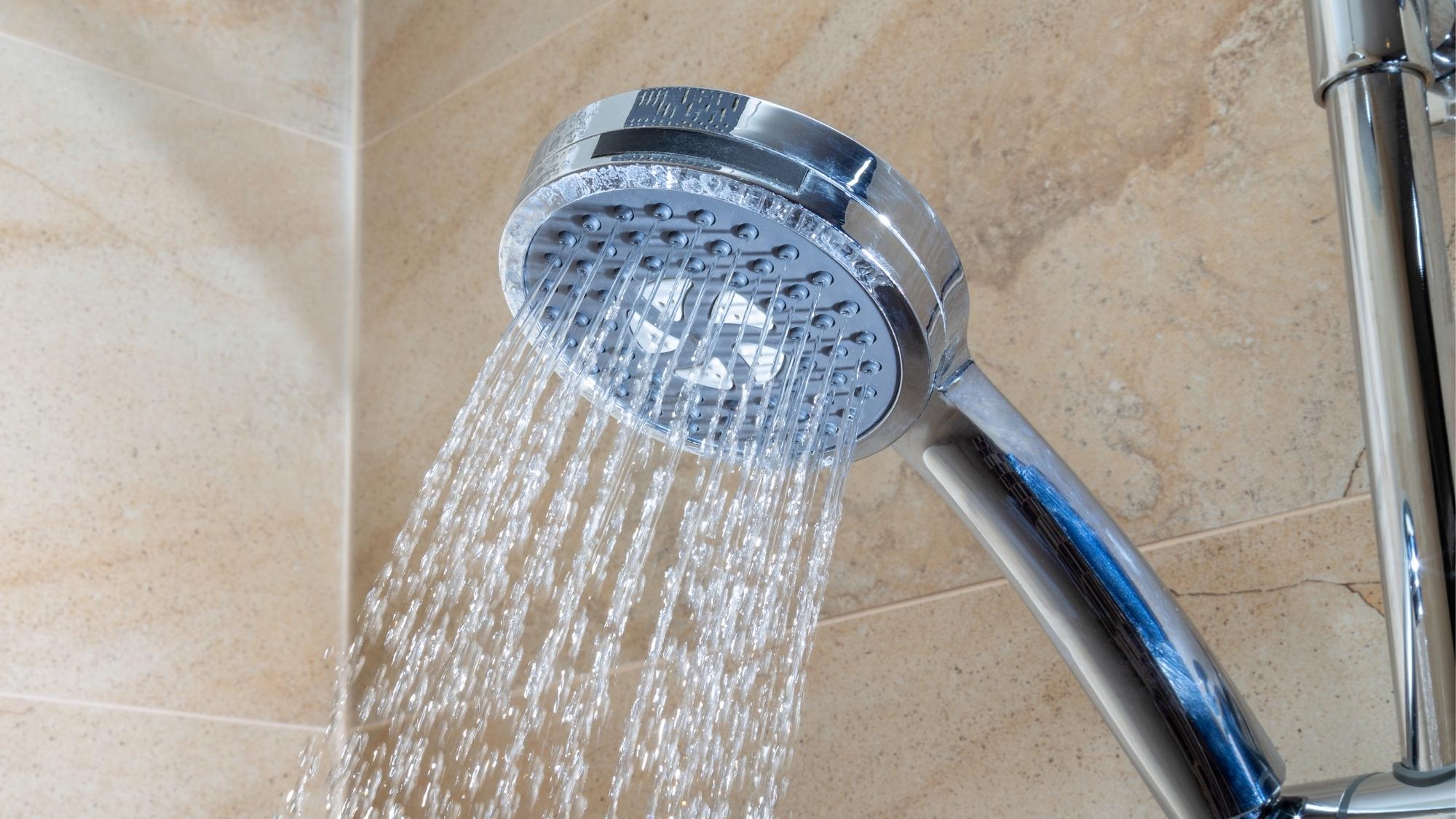Shiny silver shower head with clear water spraying from it