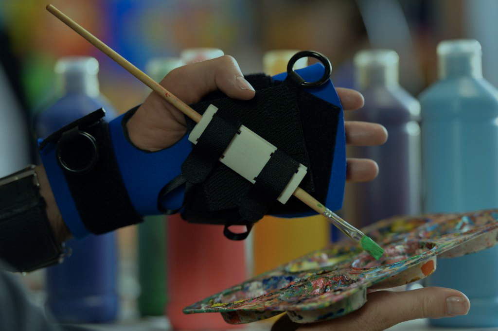 |A young man in a wheelchair smiles with a woman in red next to him|A younger woman accompanies an older woman using the evolvable walking aid|A young child wear headphones as she uses Near Field Communication technology