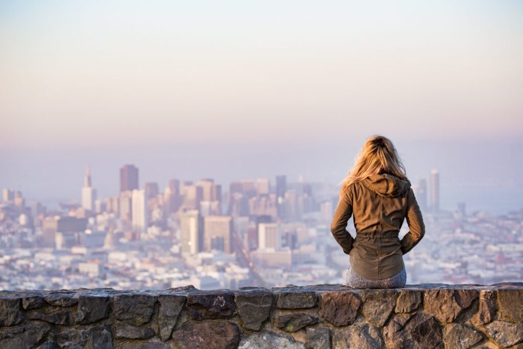 A woman sits on a wall with her back to us as she looks out of the city sprawled out in front of her|A slide showing the details of the EUSIC Challenge Plastic Waste competition 2019