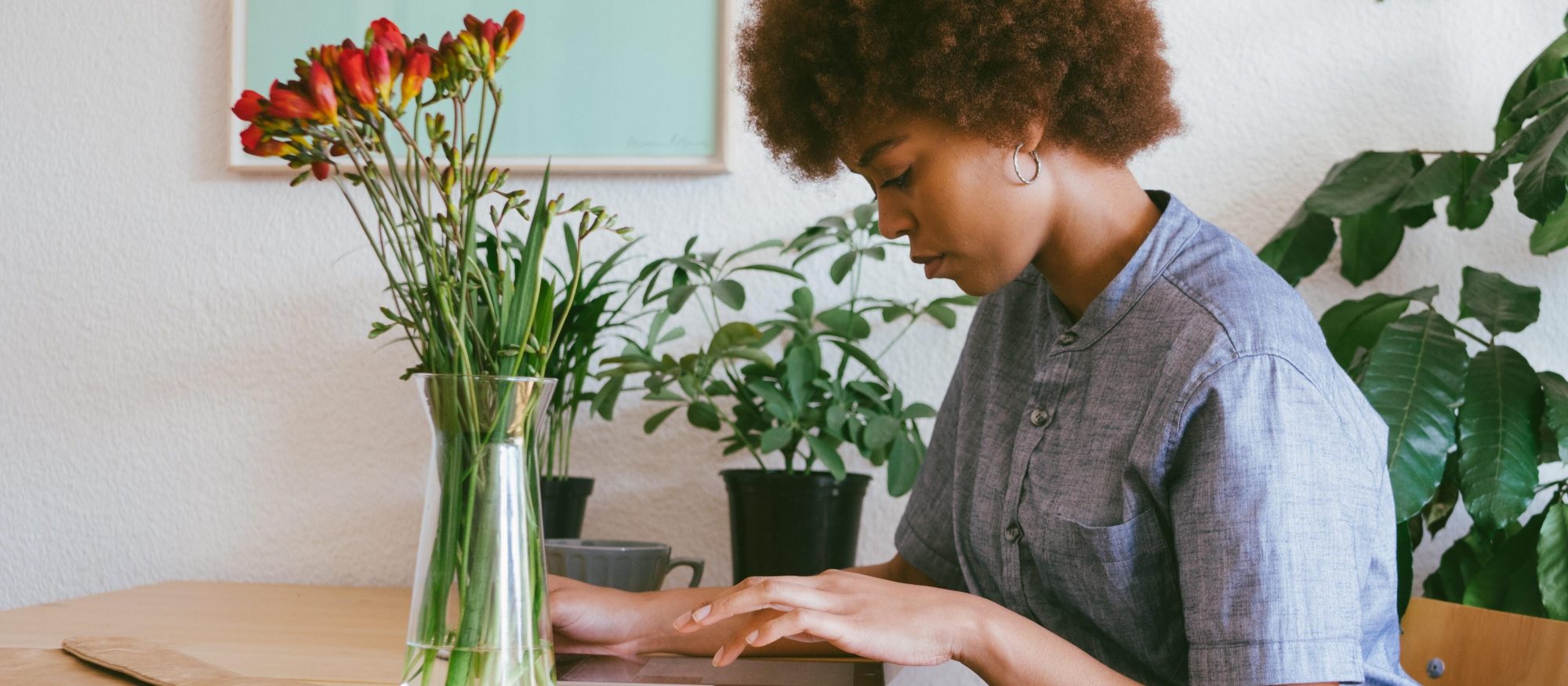 Someone who presents as female sits at a table browsing an iPad. There are flowers in a vase on the table.|A demonstration of SortYourFuture.com