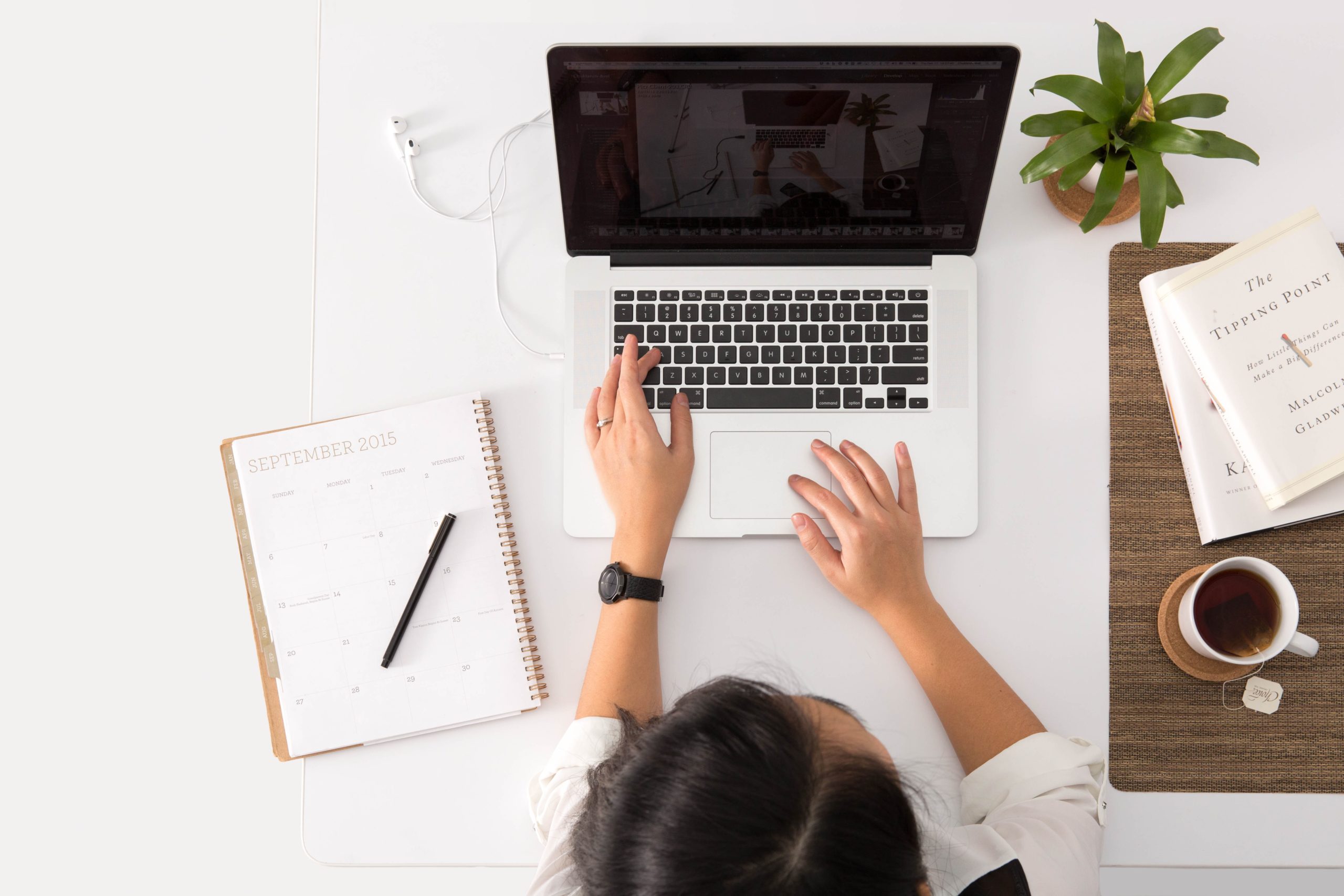 An overhead view of a woman working on a laptop|A close up of a woman in a yellow jumper working at a laptop
