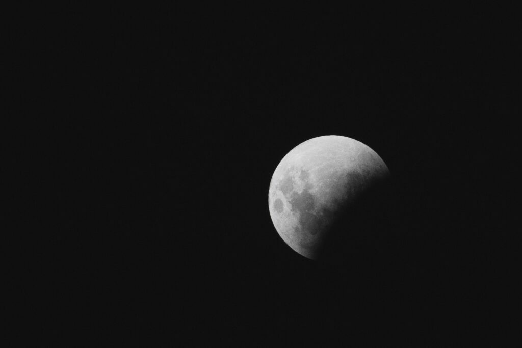 A dark background with the moon partially visible on right half of the image|Image of an astronaut in space