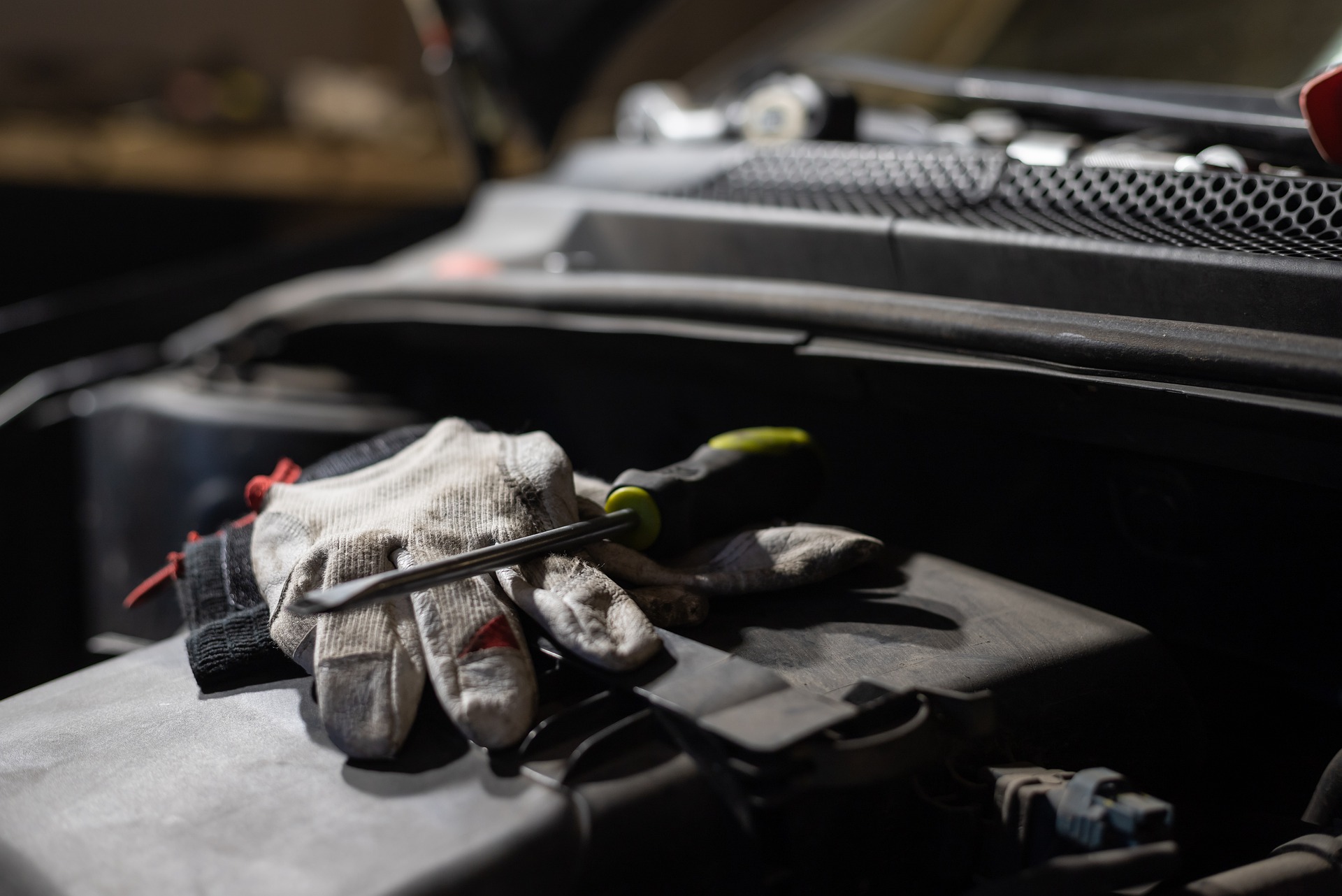 A glove and a screwdriver sit next to a car engine|Green illustration of a vehicle