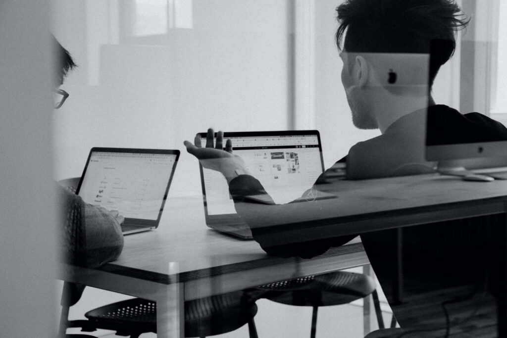 A black and white photo of two people sat at laptops
