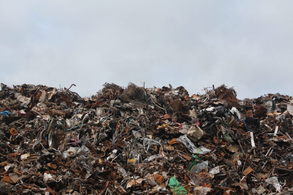 A landfill site full of rubbish|A large group of people seated at long tables outside