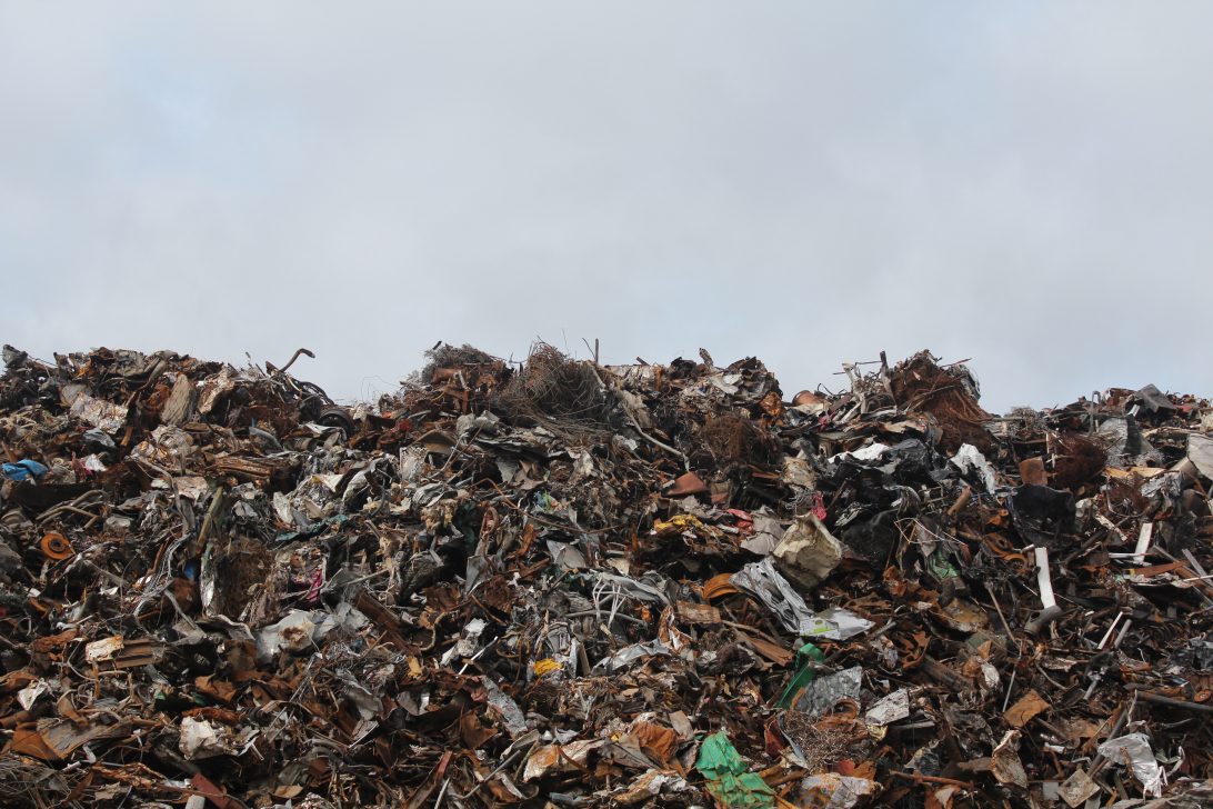 A landfill site full of rubbish|A large group of people seated at long tables outside