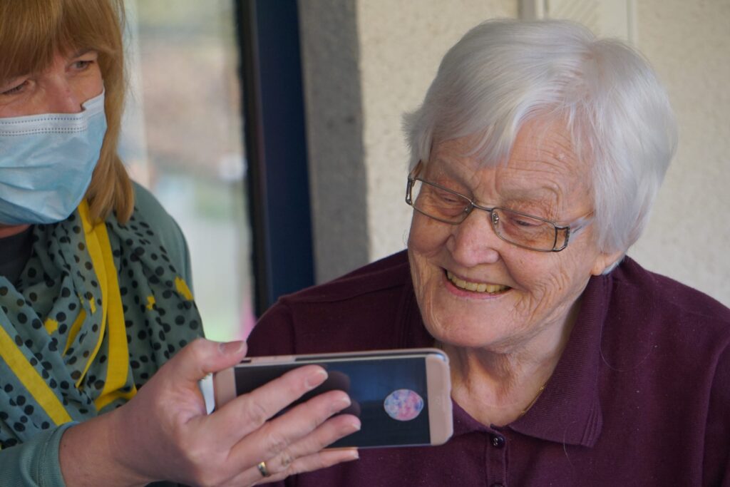 A grey haired woman looks at a phone|The prize received entries from innovators on every continent. Of the applications entered