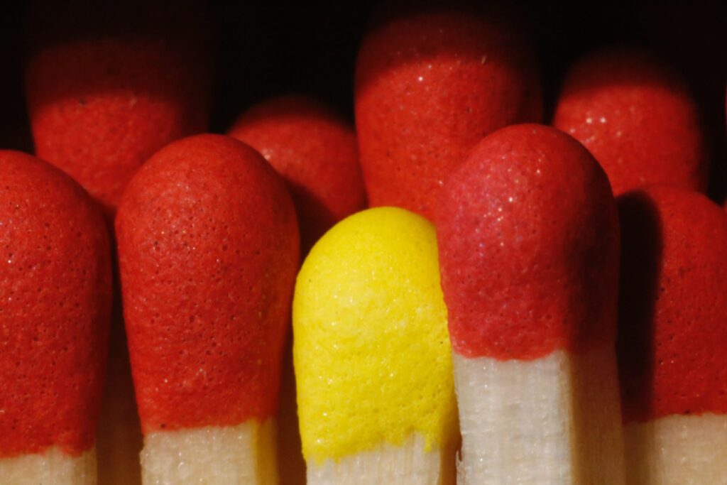 A collection of red matchsticks with one yellow peeping out|Four graphs showing the impact of evaluator gender on applicant scores