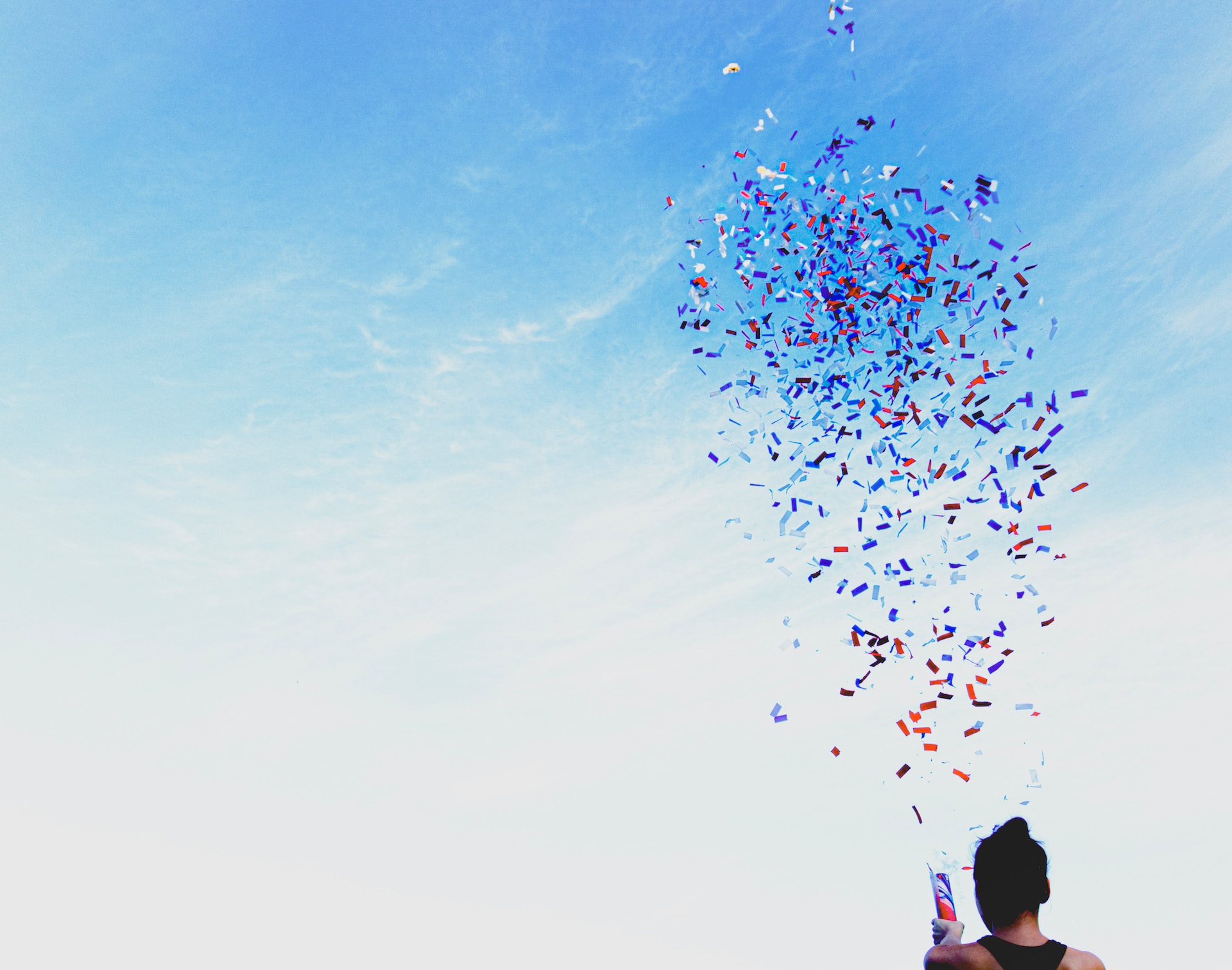 silhouette of a person releasing a party popper into the sky